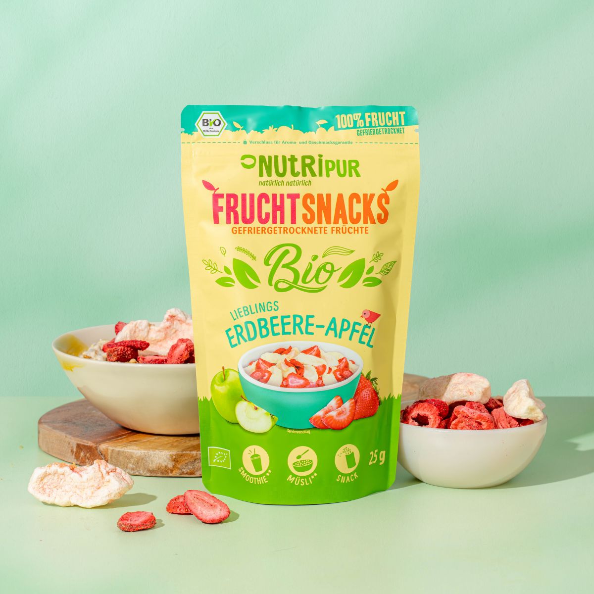 Beutel mit gefriergetrockneten Erdbeere-Apfel-Früchten. Schalen mit Früchten, lose Früchte. Bio-Siegel und 100% Frucht-Logo.