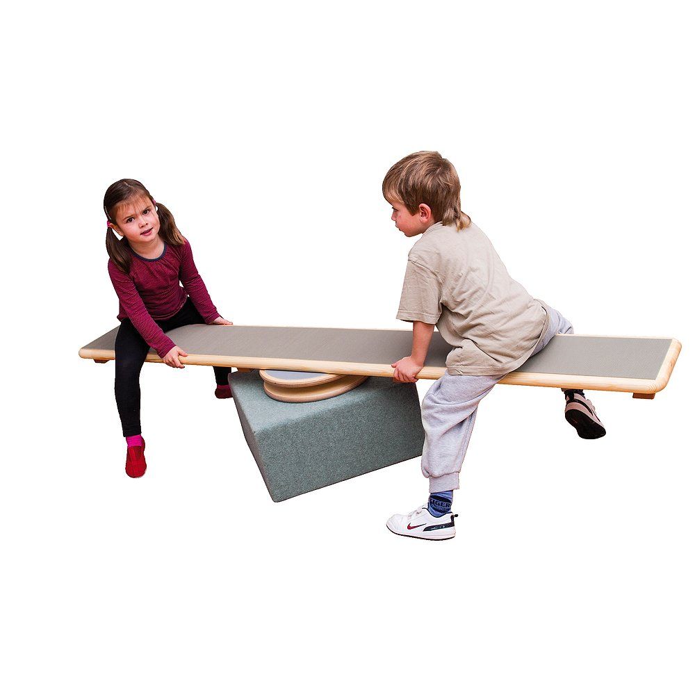 Zwei Kinder balancieren auf einem Karussell-Element. Holzkonstruktion mit Drehscheibe und Sitzfläche. Kinder halten sich fest.