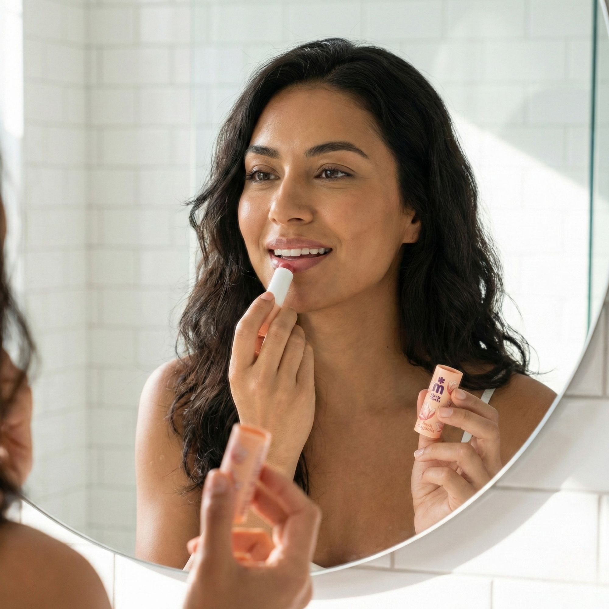 Frau trägt Lippenbalsam auf. Spiegelbild. Lippenbalsam-Produkt in der Hand. Produktname und Logo sichtbar.