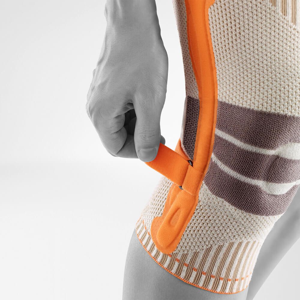 Bauerfeind Kniebandage mit seitlicher Stabilisierung, orangefarbenem Bügel.