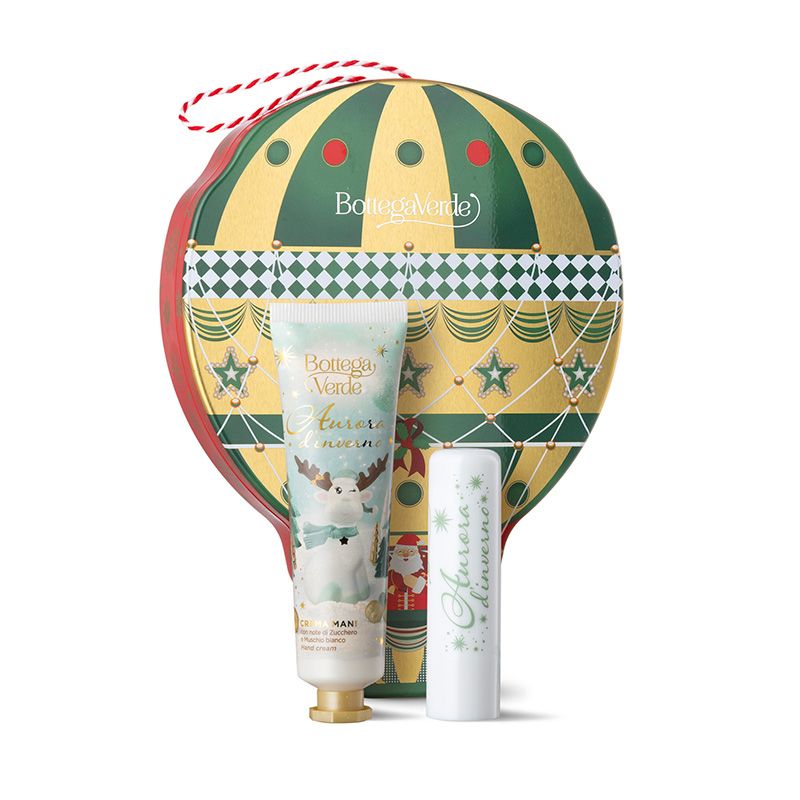 Confezione regalo natalizia Bottega Verde Aurora d'inverno, in un packaging a forma di mongolfiera. Contiene una crema mani e un balsamo labbra. L'imballaggio è dorato con dettagli verdi e rossi. I prodotti sono decorati con illustrazioni invernali.