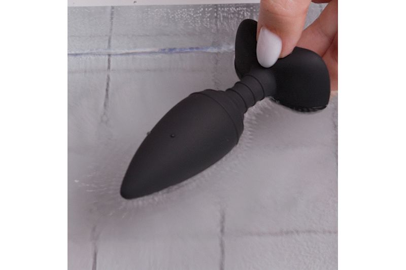 Schwarzer Analplug, gehalten von einer Hand. Der Plug hat eine konische Form und eine geriffelte Mittelpartie.