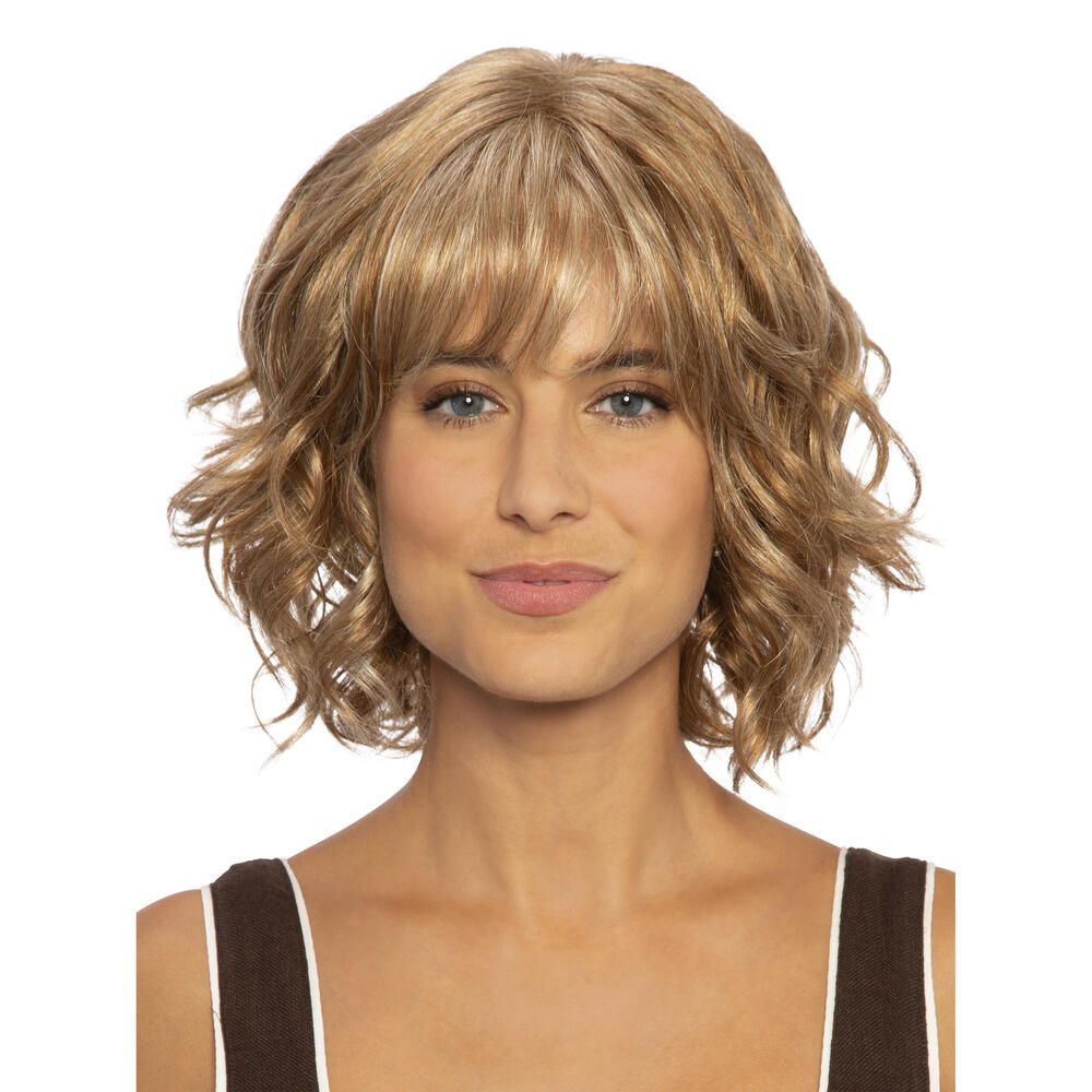 Perücke Capri, blond, gewellt, mit Pony. Frau mit Perücke vor weißem Hintergrund. Schulterlange Haare.