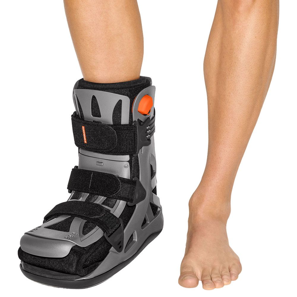 Grauer und schwarzer Gehgips mit Klettverschlüssen und orangefarbenem Einstellknopf am Bein.
