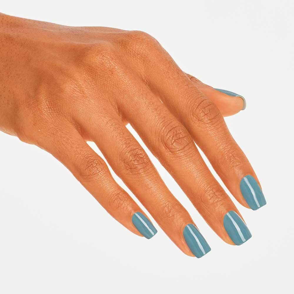 Hand mit blau-grau lackierten Nägeln. Die Nägel sind quadratisch geformt. Ein weißer Streifen verläuft entlang der Mitte.