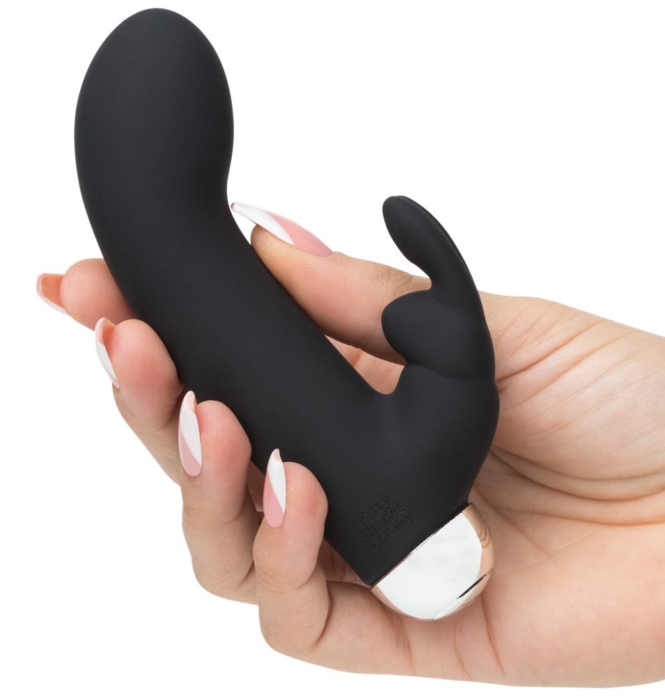 Schwarzer Rabbit-Vibrator in einer Hand gehalten. Mit zwei Vorsprüngen, einem für die Klitoris und einem für die vaginale Stimulation. Silberner Sockel.