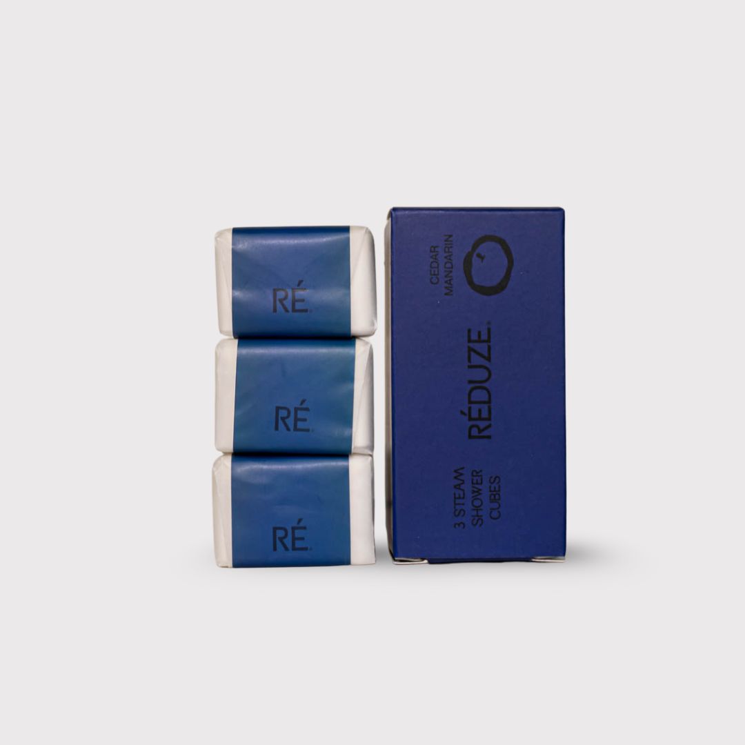 3 Duschwürfel und eine Box. Aufschrift: RÉ, 3 Steam Shower Cubes, Cedar Mandarin.