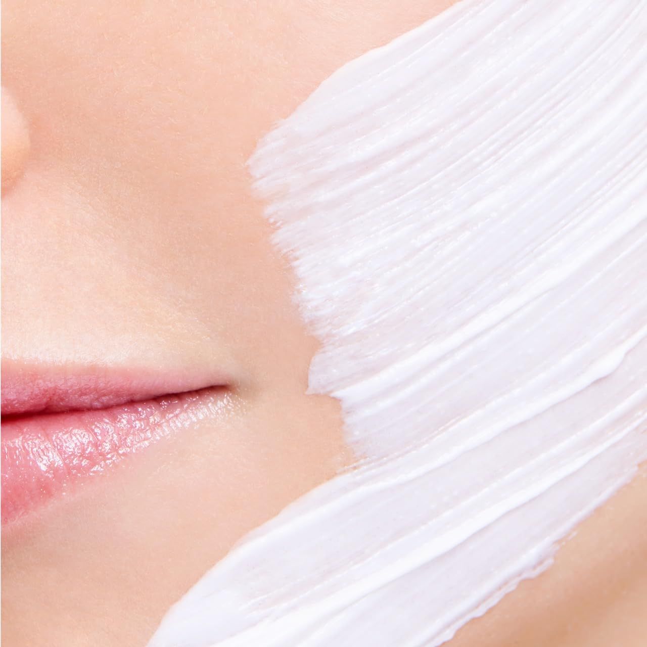 Weißes Produkt auf Haut aufgetragen. Nahaufnahme von Lippen und Haut. Textur sichtbar.