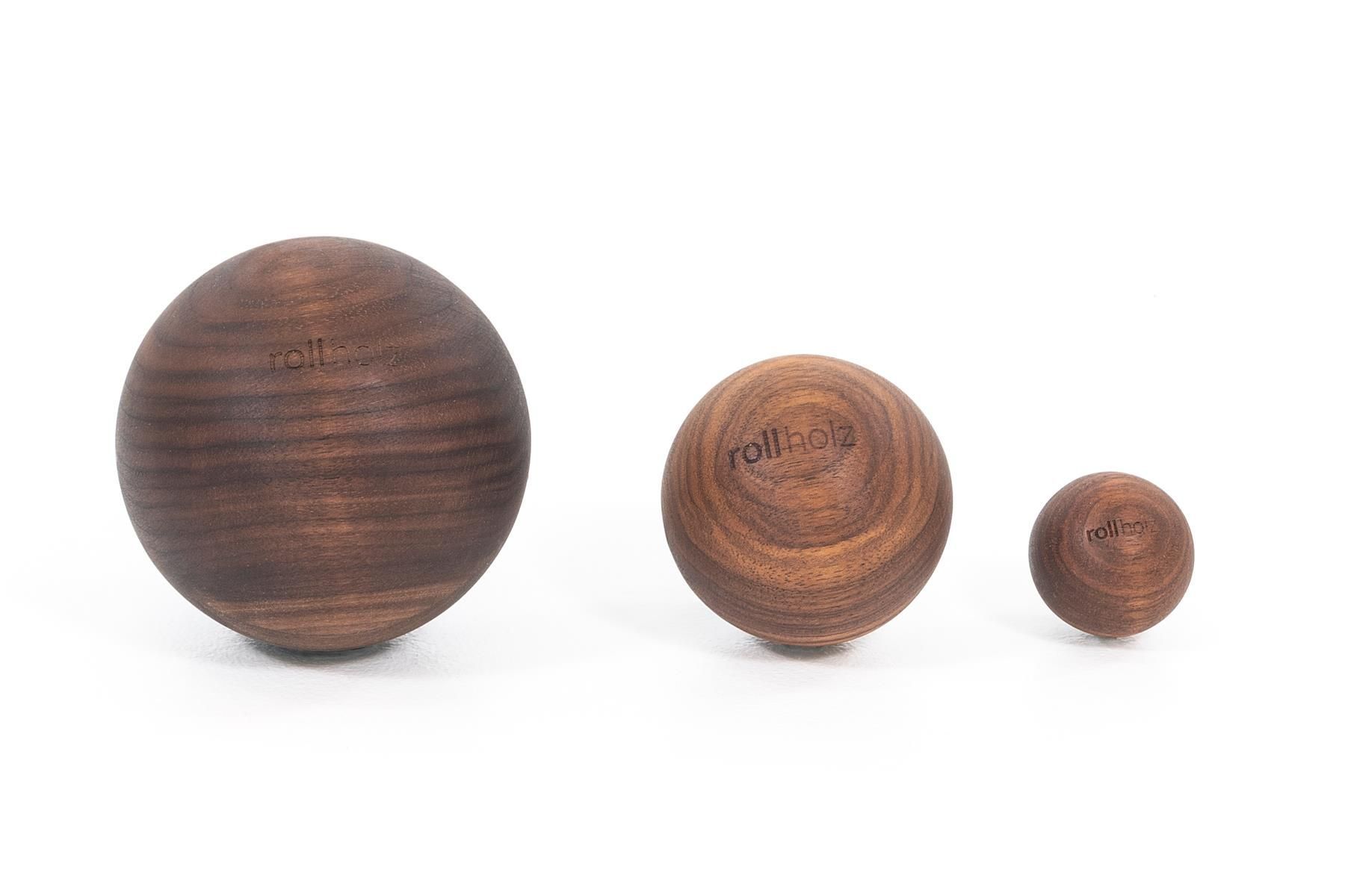 Drei Walnuss-Faszienbälle unterschiedlicher Größe. Der größte Ball links, der kleinste rechts. Alle Bälle haben die Aufschrift rollholz.