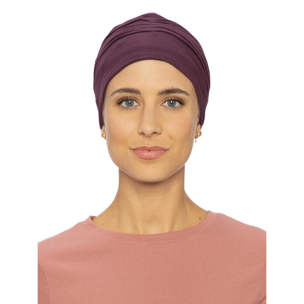 Burgunderfarbener Turban. Frontansicht einer Frau, die ihn trägt. Einfarbiges Design mit gerüschter Textur. Angenehmes Material.