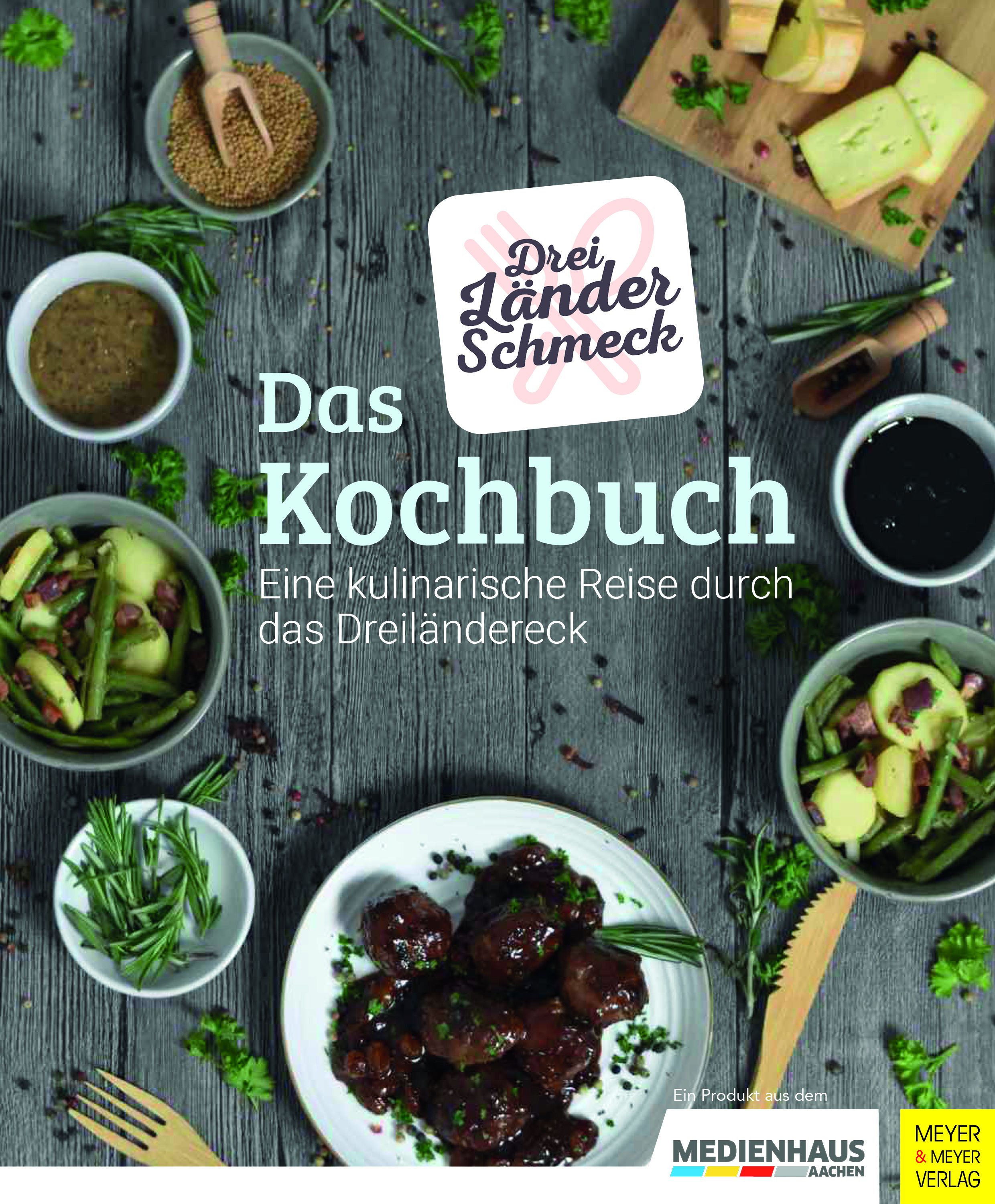 Kochbuch mit dem Titel "Das Kochbuch". Auf dem Cover steht "Drei Länder Schmeck". Umgeben von Speisen und Zutaten.