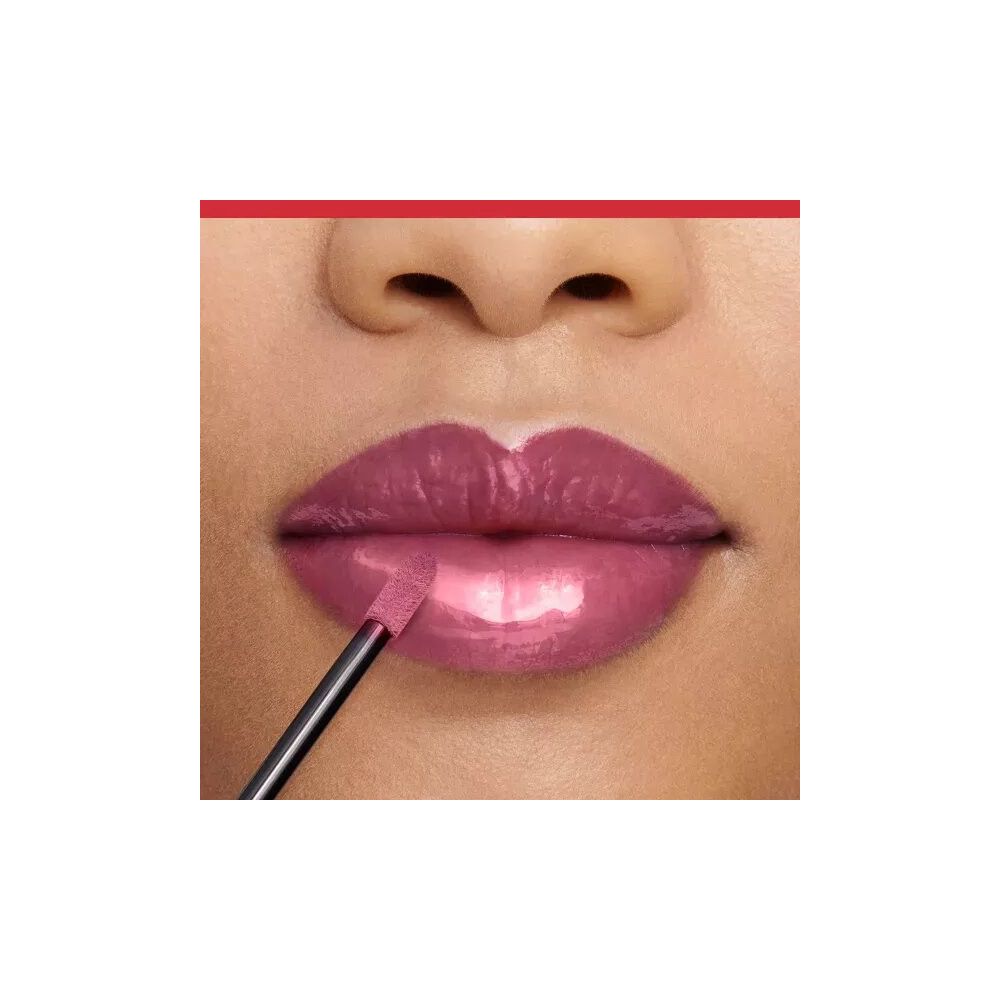 Nahaufnahme von Lippen mit aufgetragenem Lipgloss. Applikator im Mundwinkel. Glänzender, rosafarbener Lipgloss.