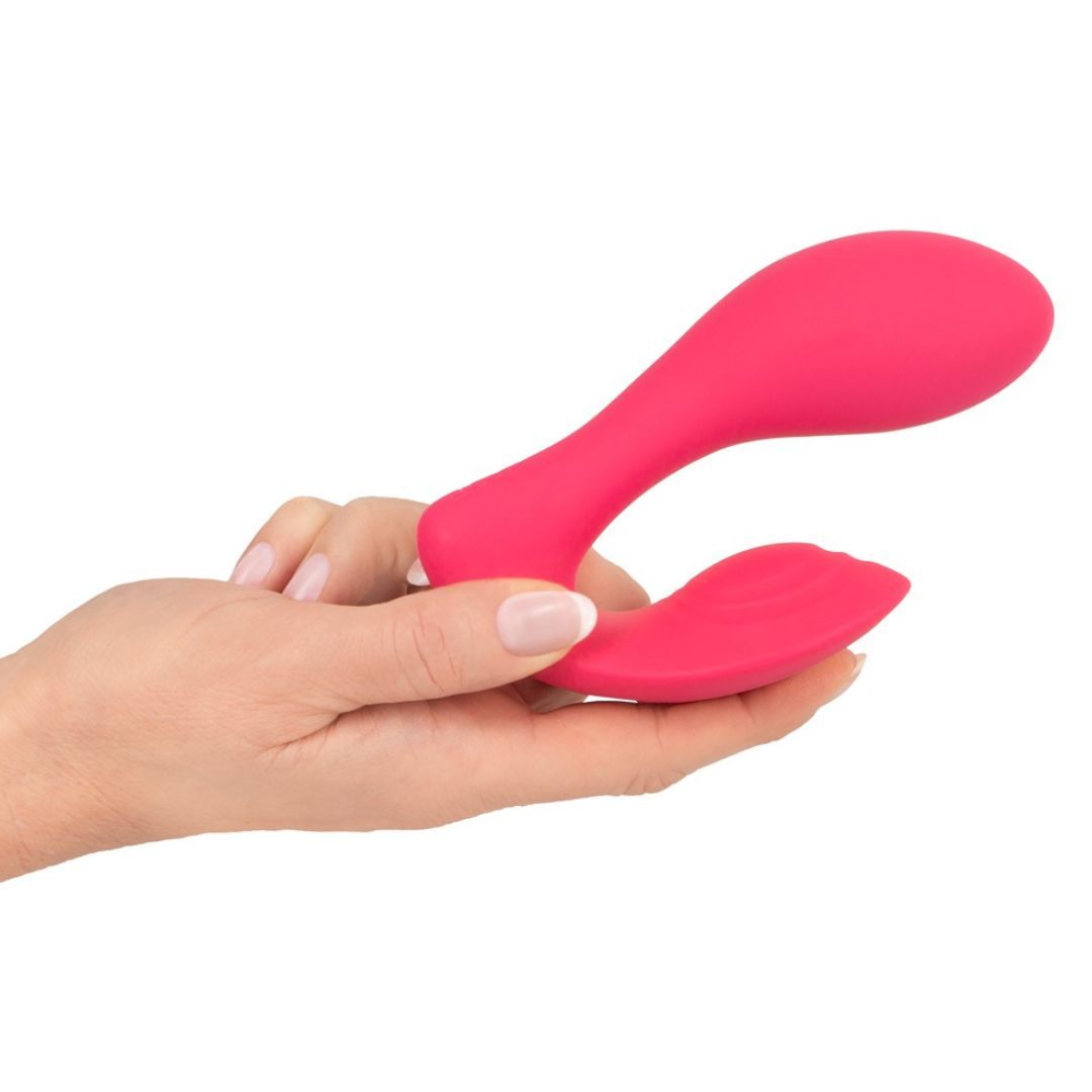 Rosa Vibrator in einer Hand gehalten. Das Produkt hat eine geschwungene Form mit zwei abgerundeten Enden.
