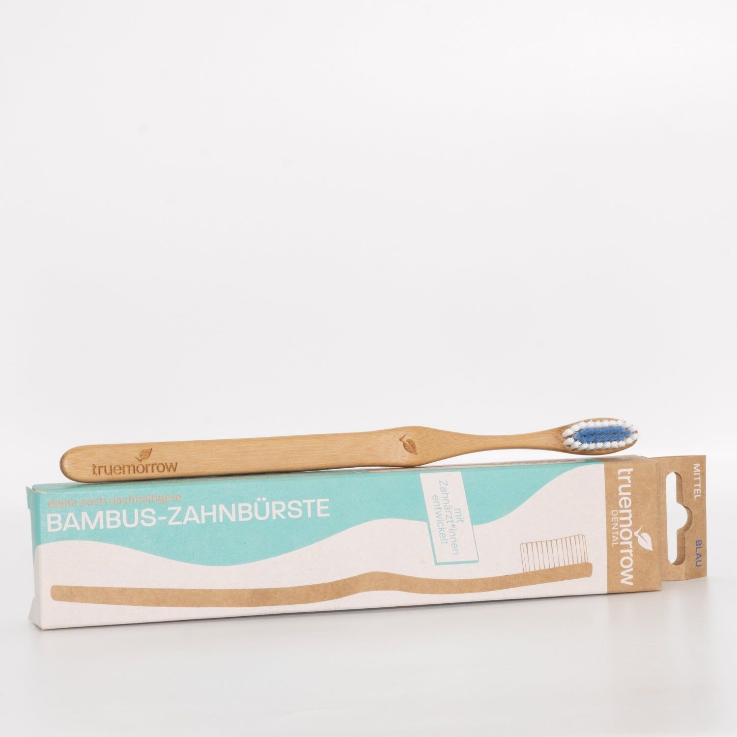 Zahnbürste aus Bambus mit blauem Borstenkopf und Verpackung. Auf der Verpackung steht "Bambus-Zahnbürste". Der Markenname "truemorrow" ist sichtbar.