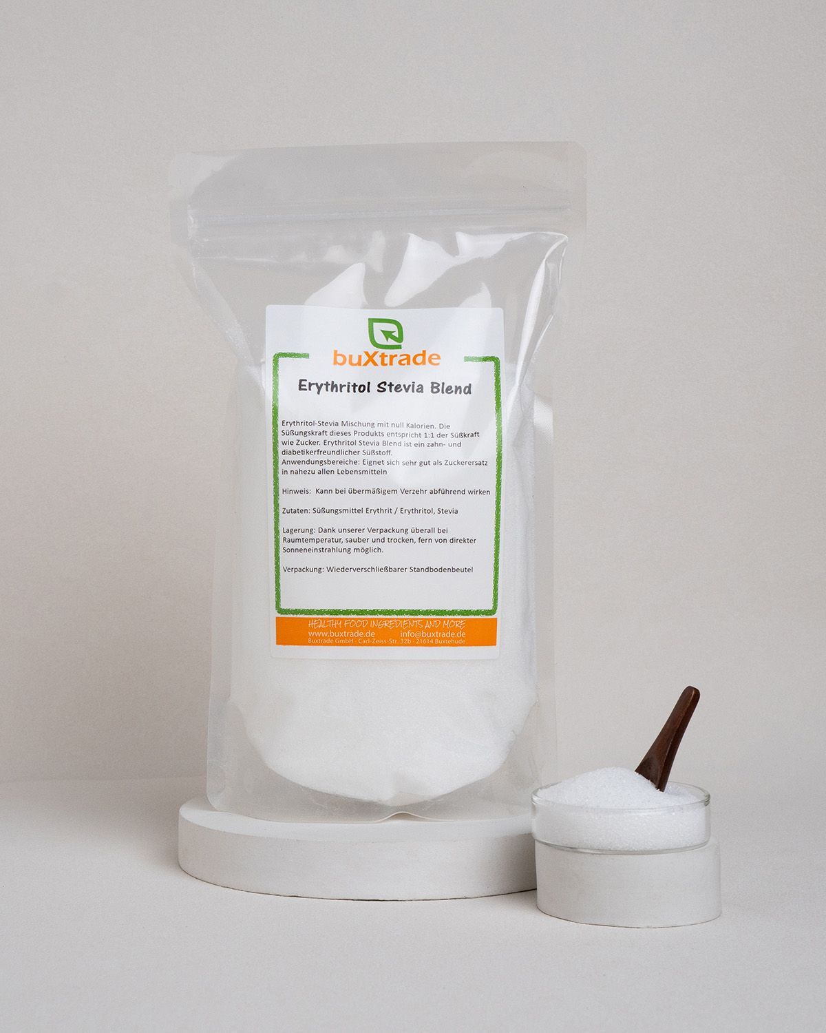 Transparente Verpackung mit weißem Pulver und Holzlöffel. Etikett mit Text: buxtrade Erythritol Stevia Blend.