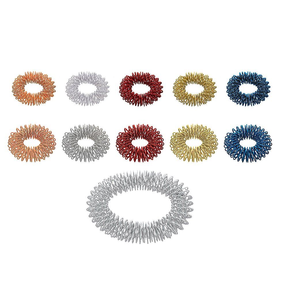 Set aus zehn Massage-Ringen in Kupfer, Silber, Rot, Gold und Blau. Ein großer Ring in Silber liegt vorne.