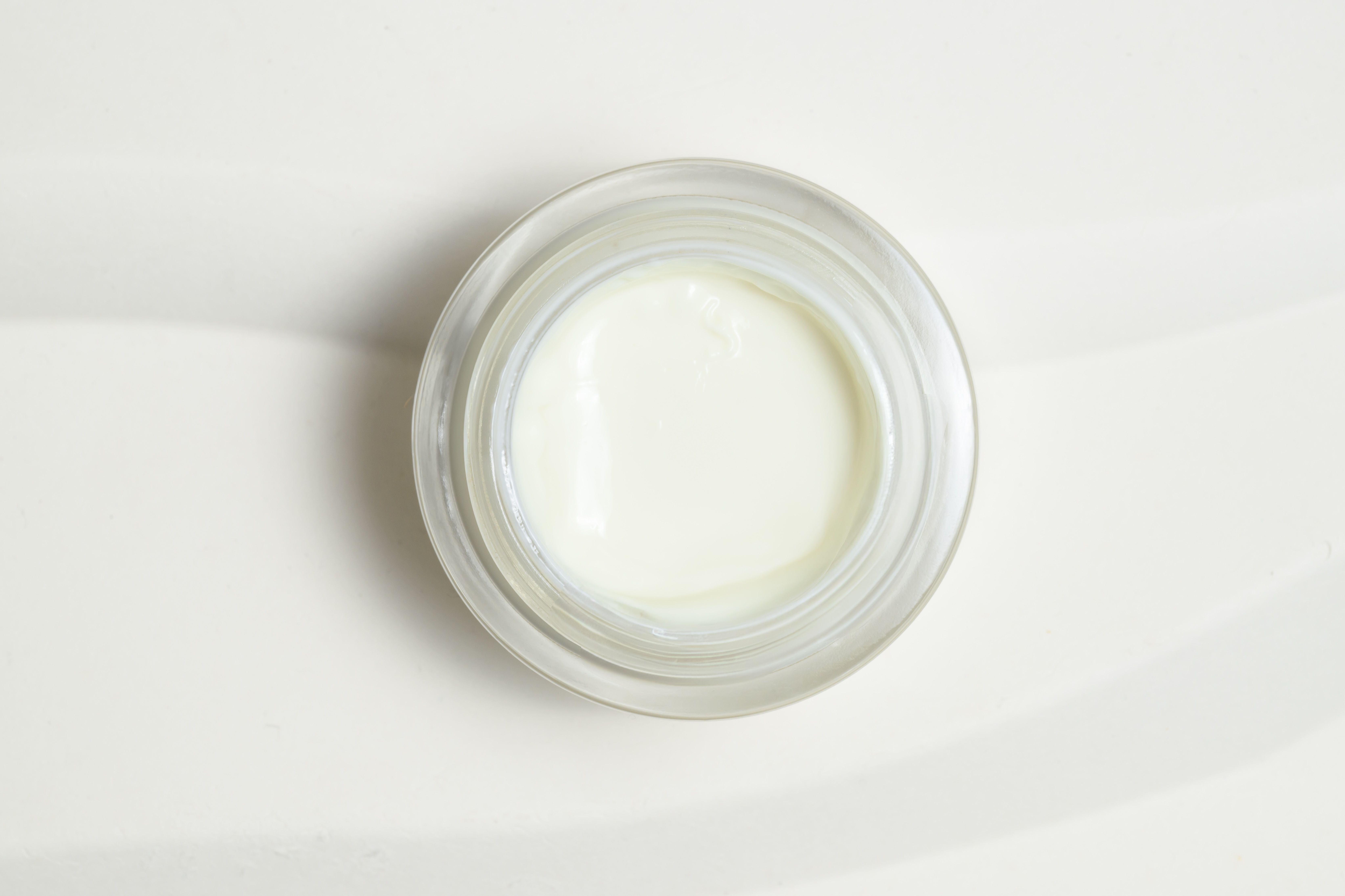 Glasbehälter mit weißer Creme. Draufsicht.