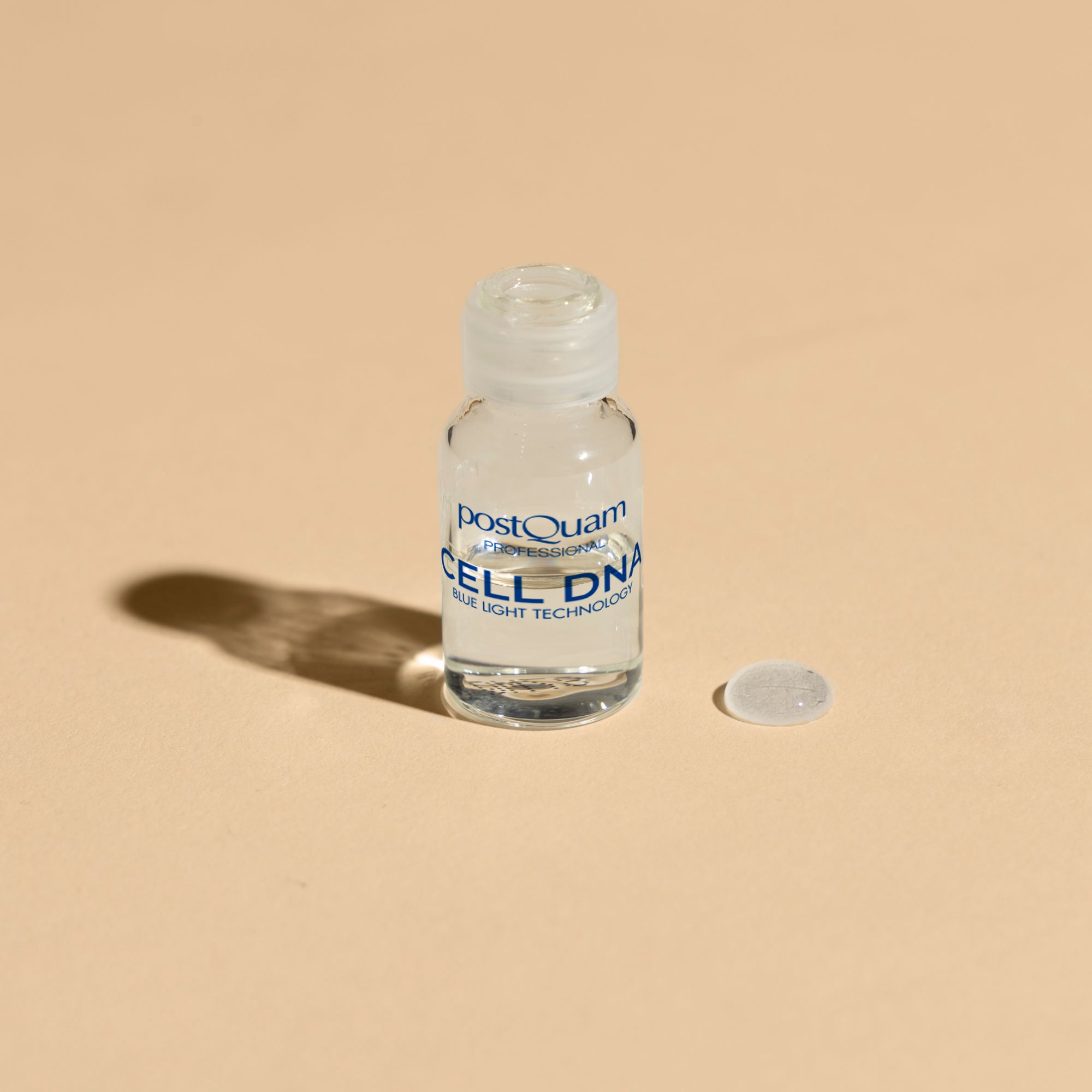 Kleine Flasche mit Flüssigkeit. Aufschrift: Postquam, CELL DNA, Blue Light Technology. Ein Tropfen daneben.