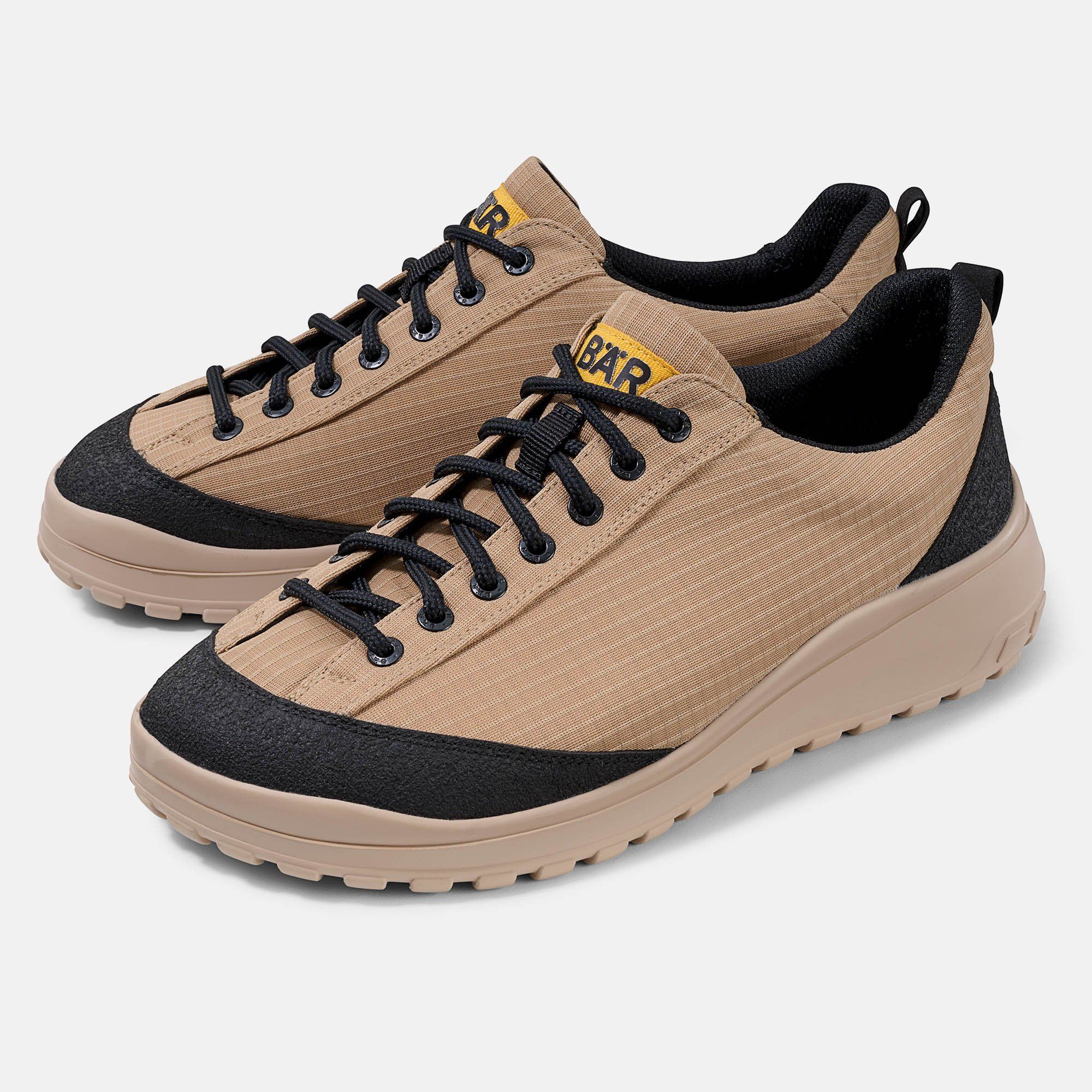 Paar beige Schnürschuhe mit schwarzem Rand und Schnürsenkeln. Gelbes Logo "BÄR".