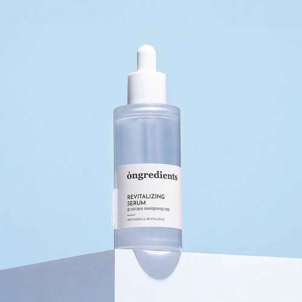 ONGREDIENTS Revitalizing Serum. Transparente Flasche mit weißem Deckel und Pipette. Auf blauem Hintergrund platziert.