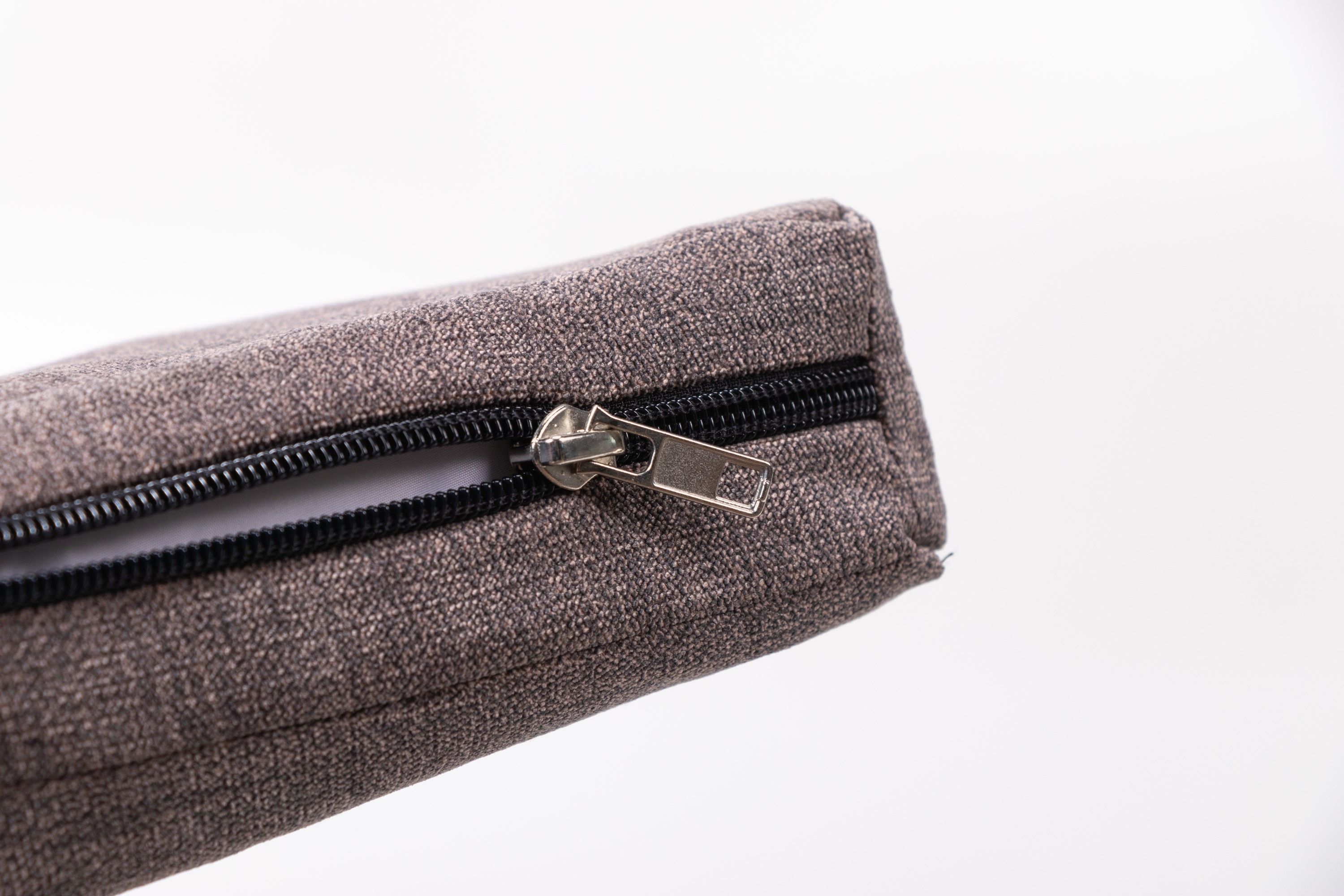 Grauer Matratzenbezug mit Reißverschluss. Der Reißverschluss ist geöffnet und zeigt das Innenleben. Nahaufnahme.