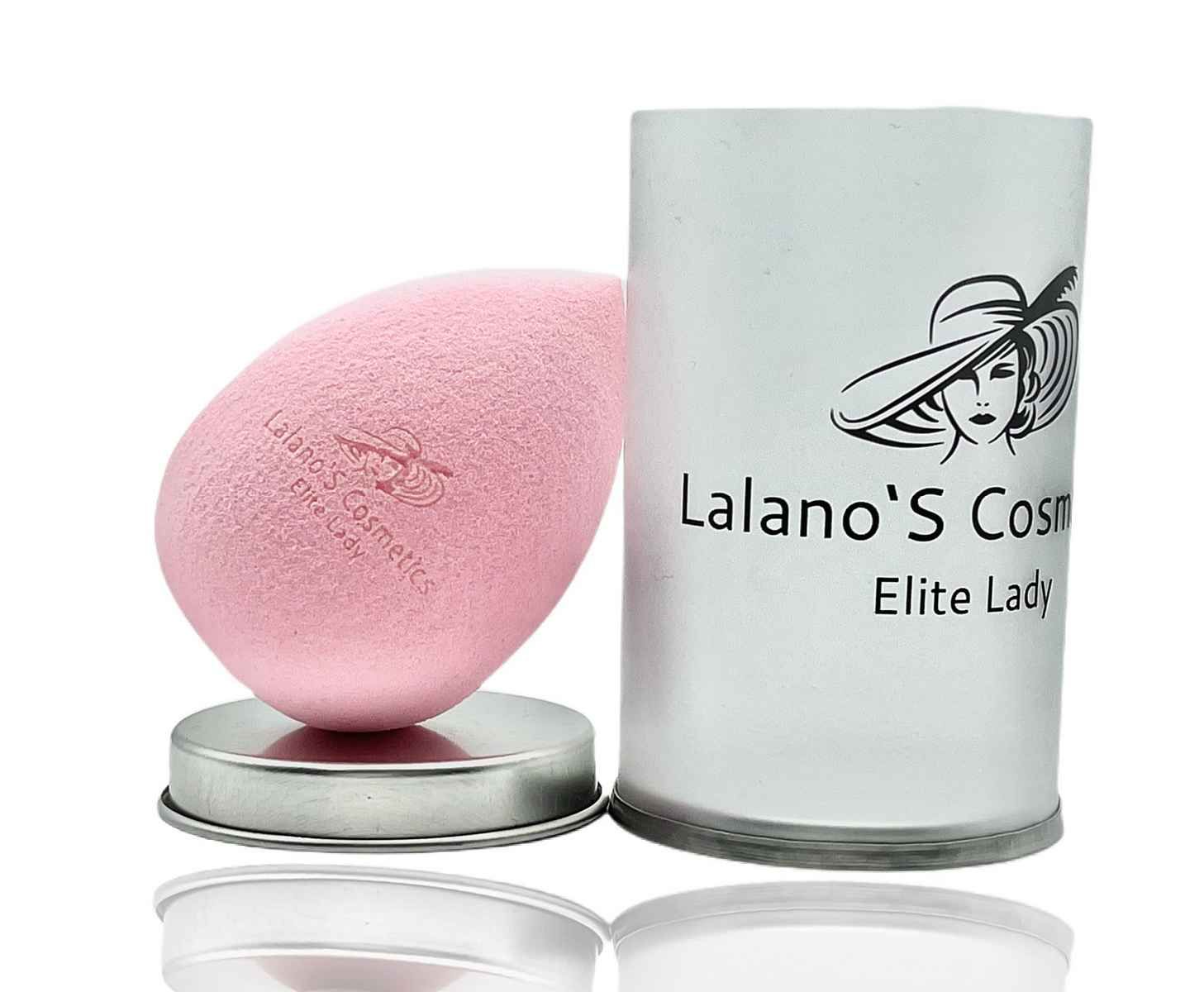 Rosa Make-up Schwamm mit Logo und Schriftzug. Steht auf einem silbernen Untersetzer neben einer zylindrischen Verpackung mit Logo.