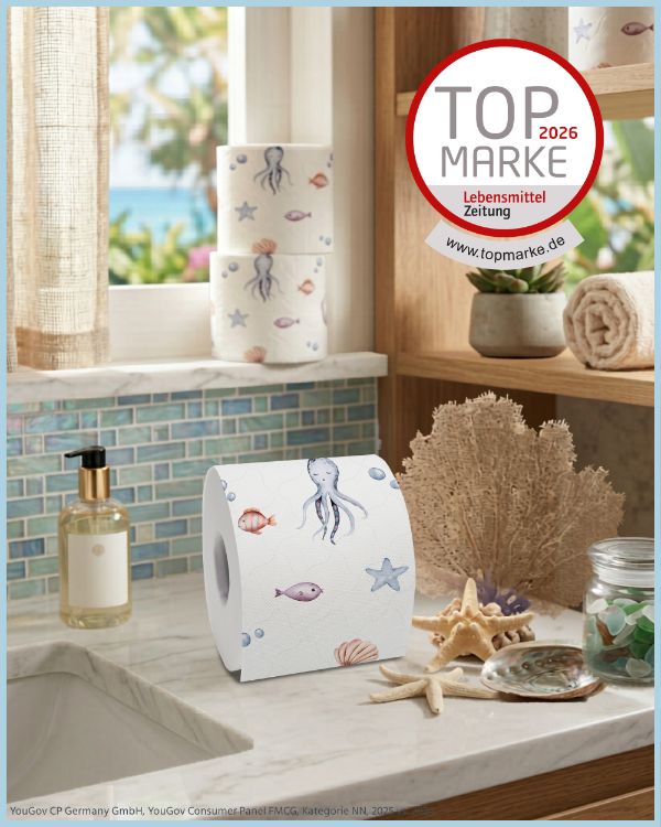 Rolle Toilettenpapier mit Meeresmotiven auf einer Marmoroberfläche. Oben: Top Marke 2026. Neben: Seife, Handtuch, Dekoration. Papier mit Tintenfisch-Motiv.