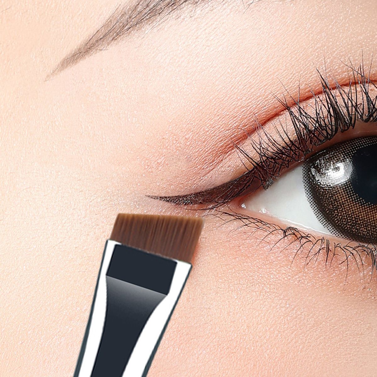 Ein schräger Augen-Make-up-Pinsel wird auf ein Auge aufgetragen, um Eyeliner zu ziehen.