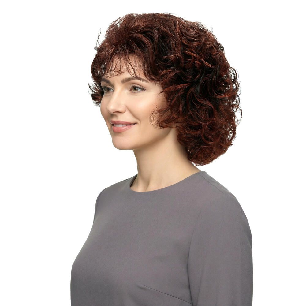 Frau mit brauner, lockiger Perücke. Seitenansicht. Graues Oberteil. Weißer Hintergrund.