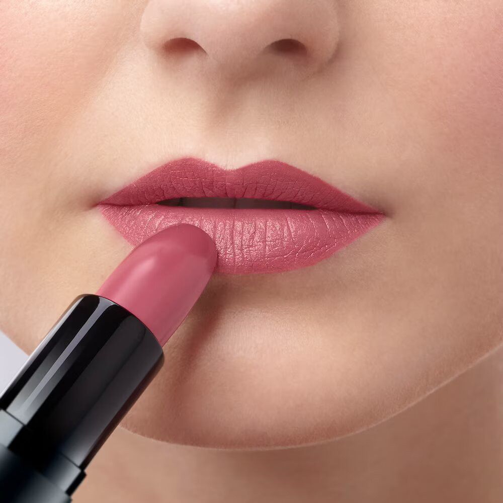Lippen, die mit einem rosafarbenen Lippenstift bemalt werden. Schwarzer Lippenstift-Halter.