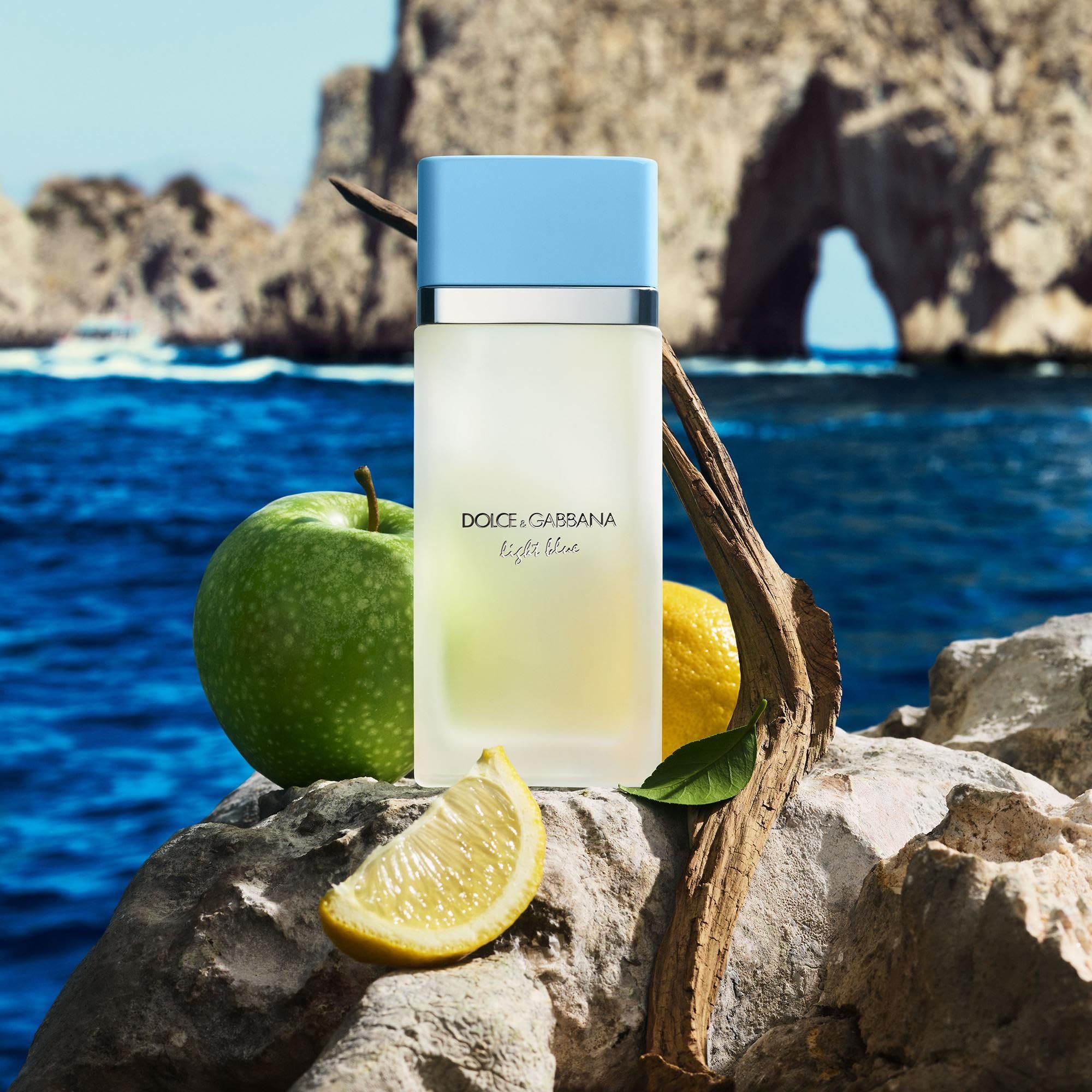 Flakon neben Apfel, Zitrone und Zweig. Aufschrift: Dolce & Gabbana Light Blue.