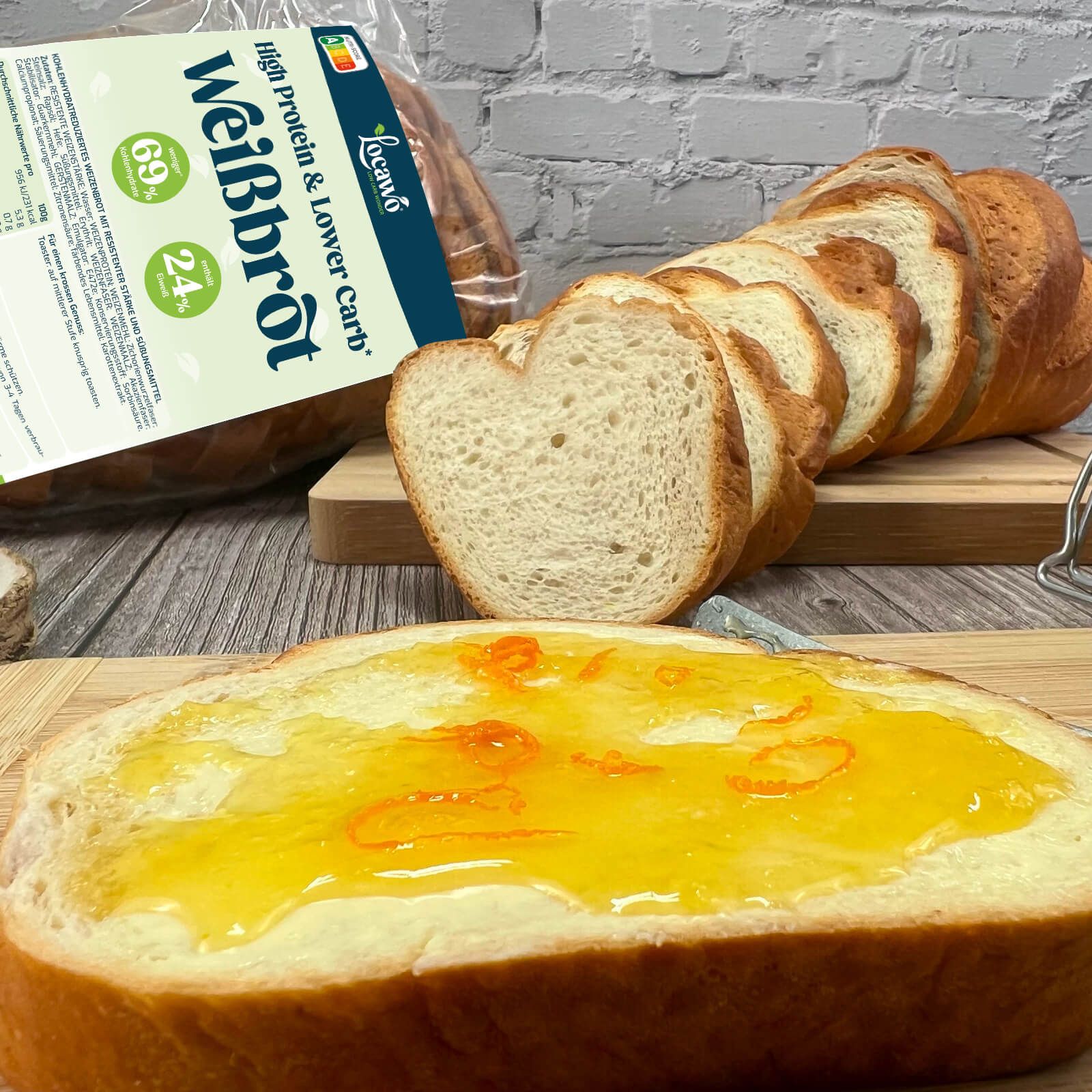 Weißbrotscheibe mit Marmelade, Messer, verpacktes Brot im Hintergrund. Aufschrift: Locawo Weißbrot. 69% Protein, 24% Kohlenhydrate.