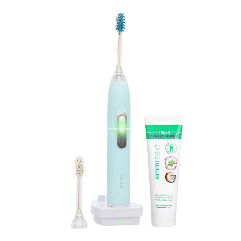 Zahnbürste Metallic Pastellblau, Ladestation, Ersatzbürste und Zahnpasta. Zahnpasta mit Aufschrift emmi-dent FRESH PROFESSIONAL.