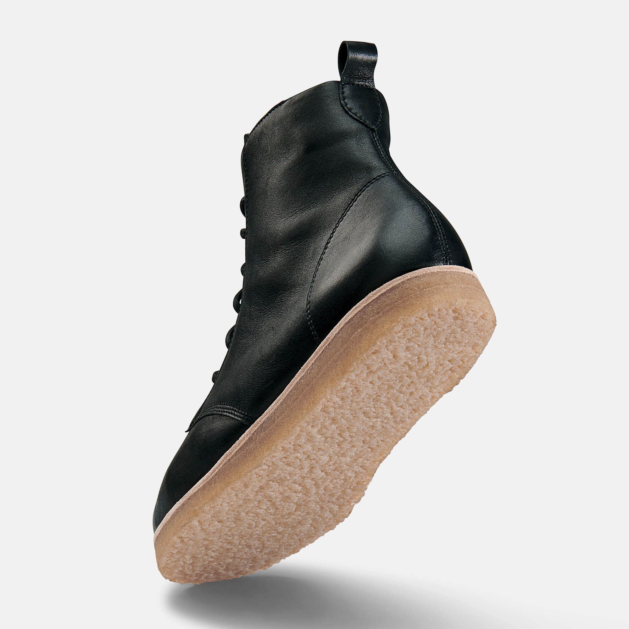 Schwarze Stiefelette mit heller Sohle. Unteransicht, Schuh leicht schräg gestellt.