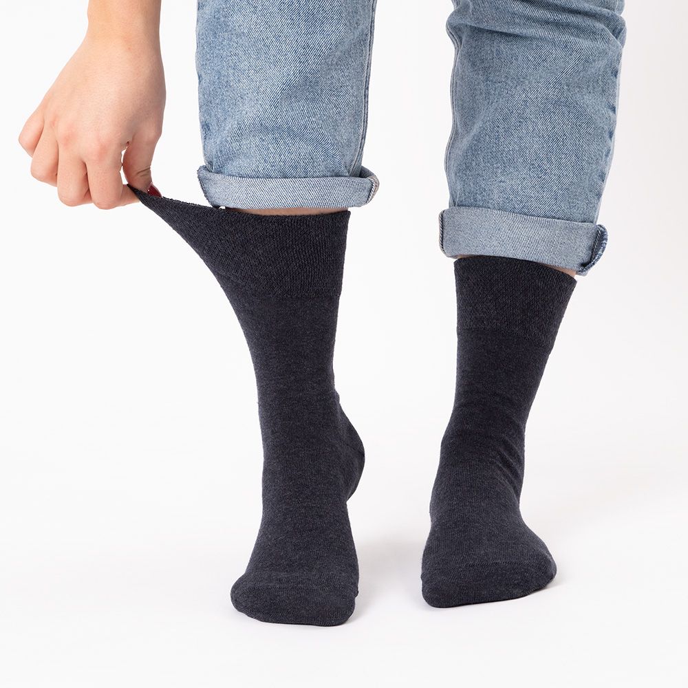 Person zieht graue Socken an. Marke Occulto am Bund. Größe 39-42.