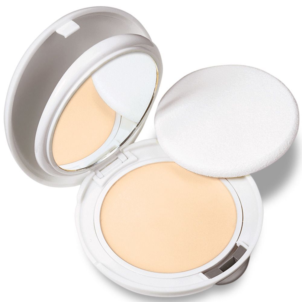 Poudre de maquillage compacte dans un boîtier blanc, miroir et houppette. Ouvert, poudre beige clair.