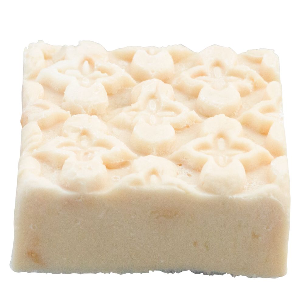 Rechteckiger, cremefarbener Seifenblock mit erhabenem, floralem Muster. Die Oberfläche ist uneben.