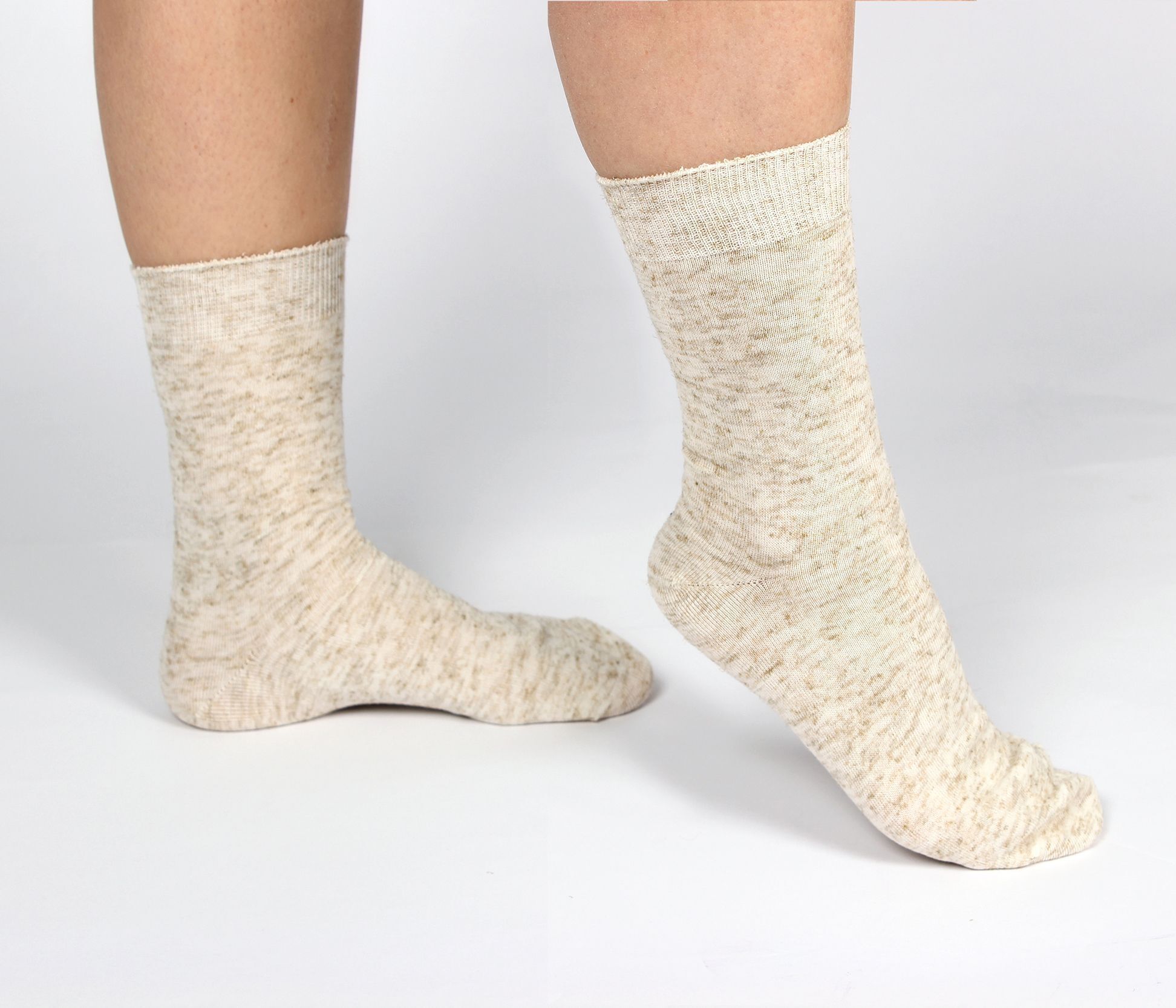 Person trägt helle Socken aus Baumwolle und Leinen. Die Socken bedecken die Füße und Knöchel. Der Hintergrund ist weiß.