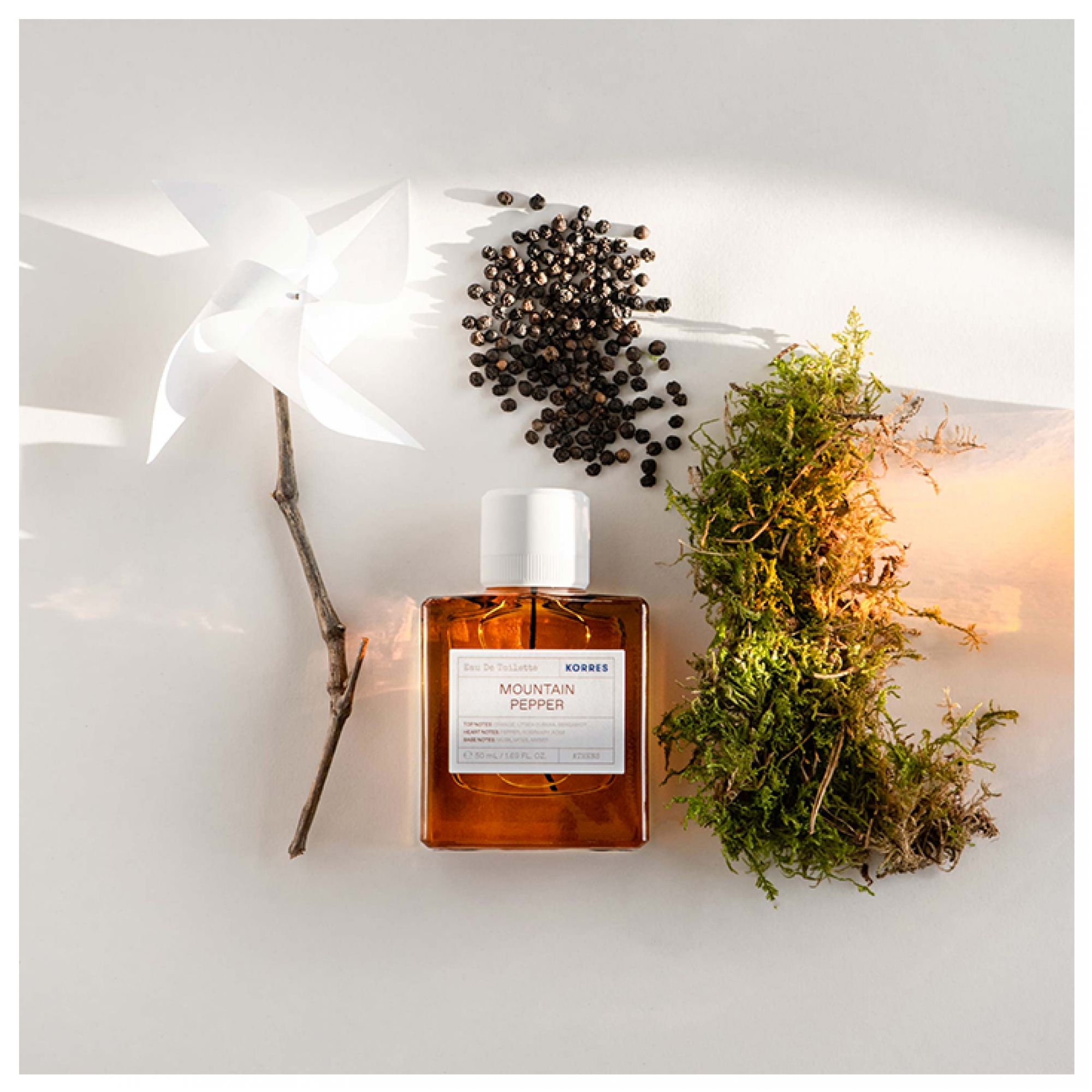 Korres Eau de Toilette Mountain Pepper Flakon mit Pfefferkörnern, Moos und einem Zweig.