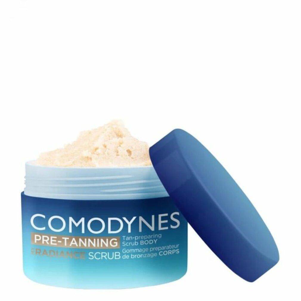 Blau-weißer Tiegel mit offenem Deckel. Produktname: COMODYNES PRE-TANNING RADIANCE SCRUB BODY. Helles Peeling sichtbar.