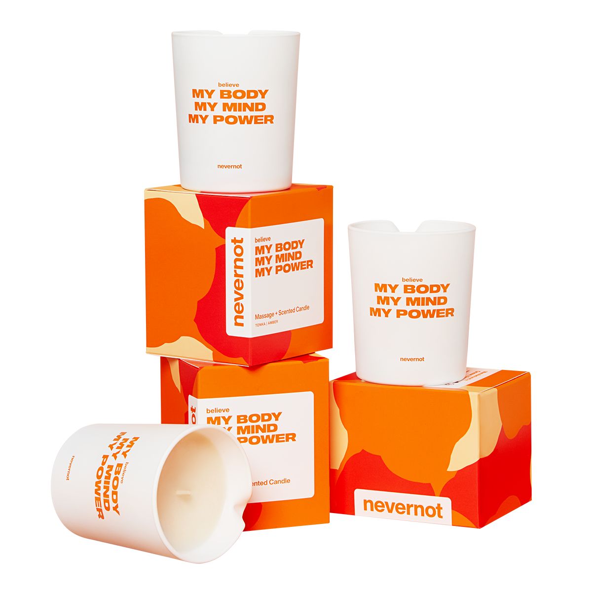 Weiße Kerzen mit Aufschrift BELIEVE MY BODY MY MIND MY POWER. Auf orangefarbenen Verpackungen und Podesten.