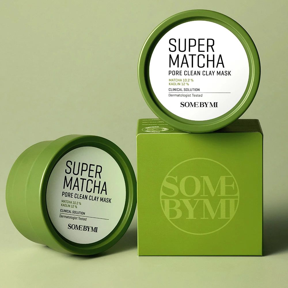 Zwei grüne Dosen und eine grüne Box. Text: Super Matcha Pore Clean Clay Mask. Marke: Some By Mi. Auf grünem Untergrund.