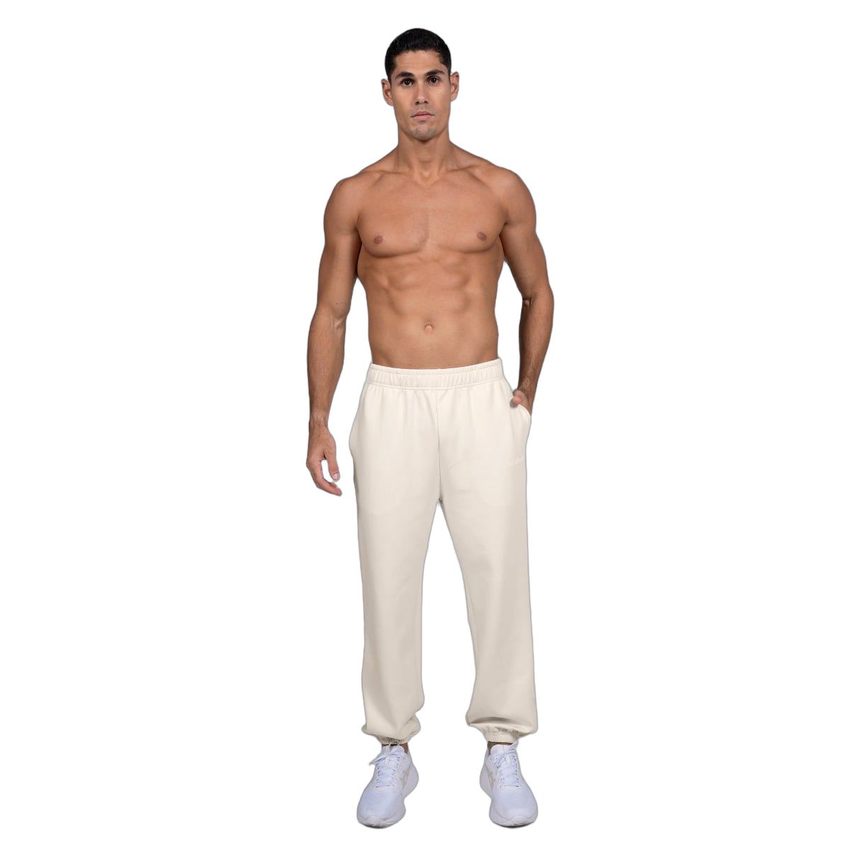 Mann trägt beige Jogginghose, Oversized-Passform, elastischer Bund, weiße Sneaker.