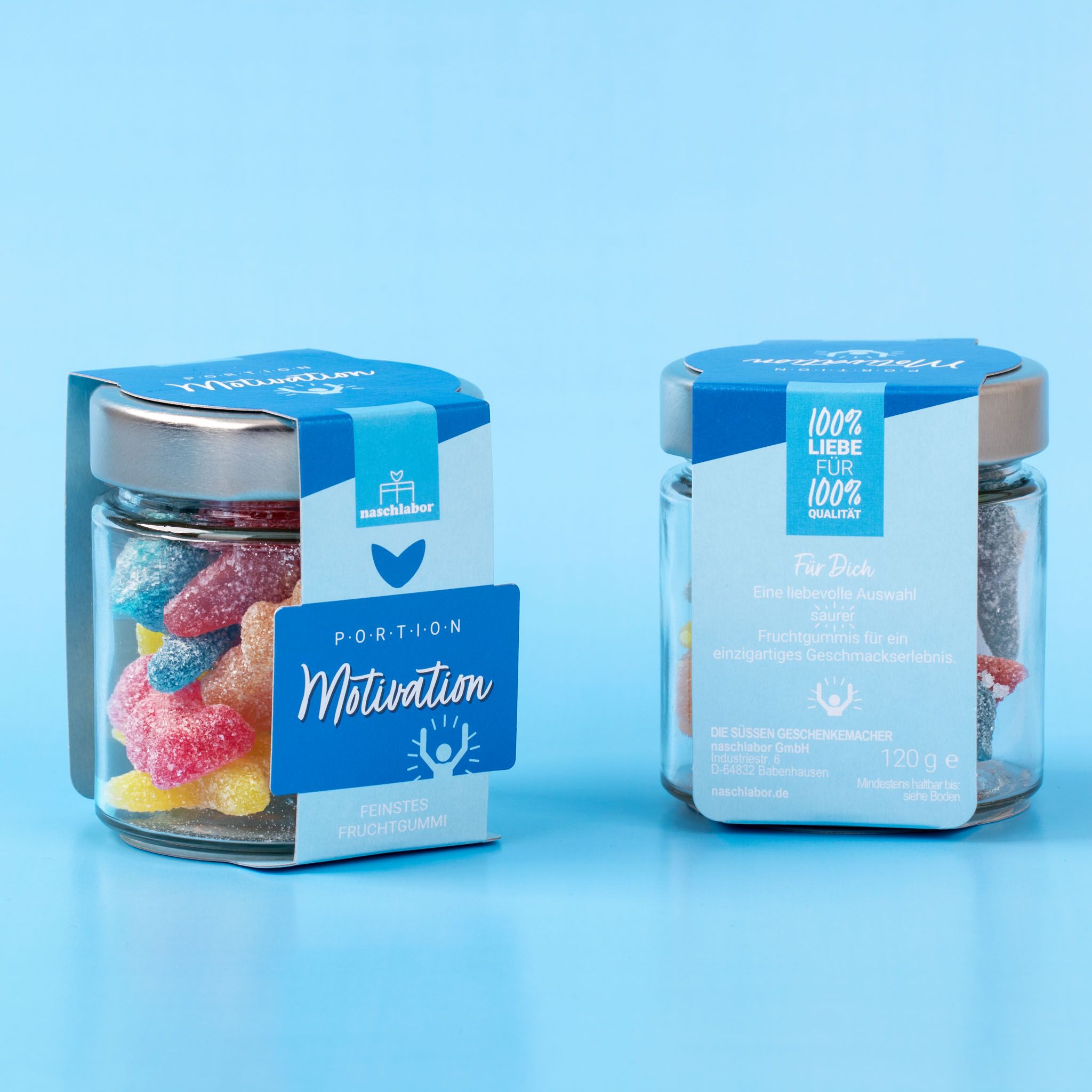 Zwei Gläser Fruchtgummi Portion Motivation. Blaue Etiketten. Aufschrift: naschlabor, Portion Motivation, feinstes Fruchtgummi. 100% Liebe für 100%.