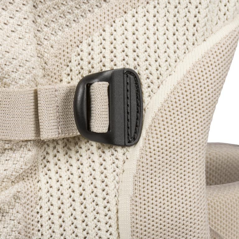 Nahaufnahme einer schwarzen Schnalle an einer beige Babytrage.