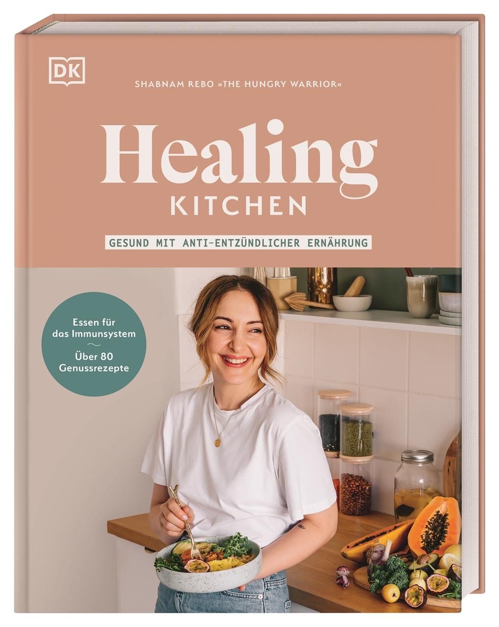 Buchcover von Healing Kitchen. Titel und Autor sind sichtbar. Frau hält Schüssel mit Essen. Hintergrund: Küche.