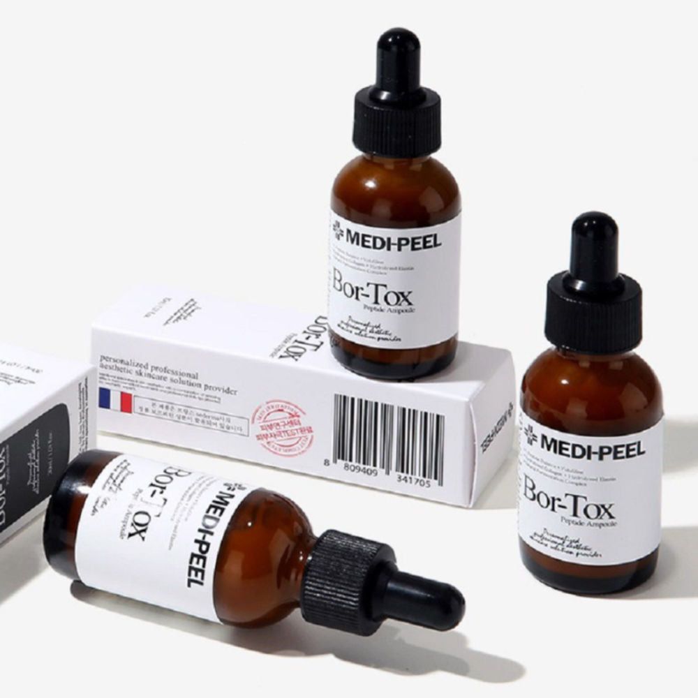 Braune Flaschen mit schwarzen Pipetten. Aufkleber mit Logo und Produktnamen. Marke: Medi-Peel. Verpackung im Hintergrund.