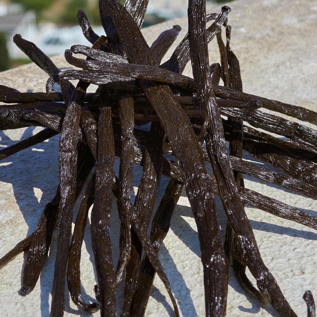 Haufen von Vanilleschoten. Die Schoten sind dunkelbraun und länglich.