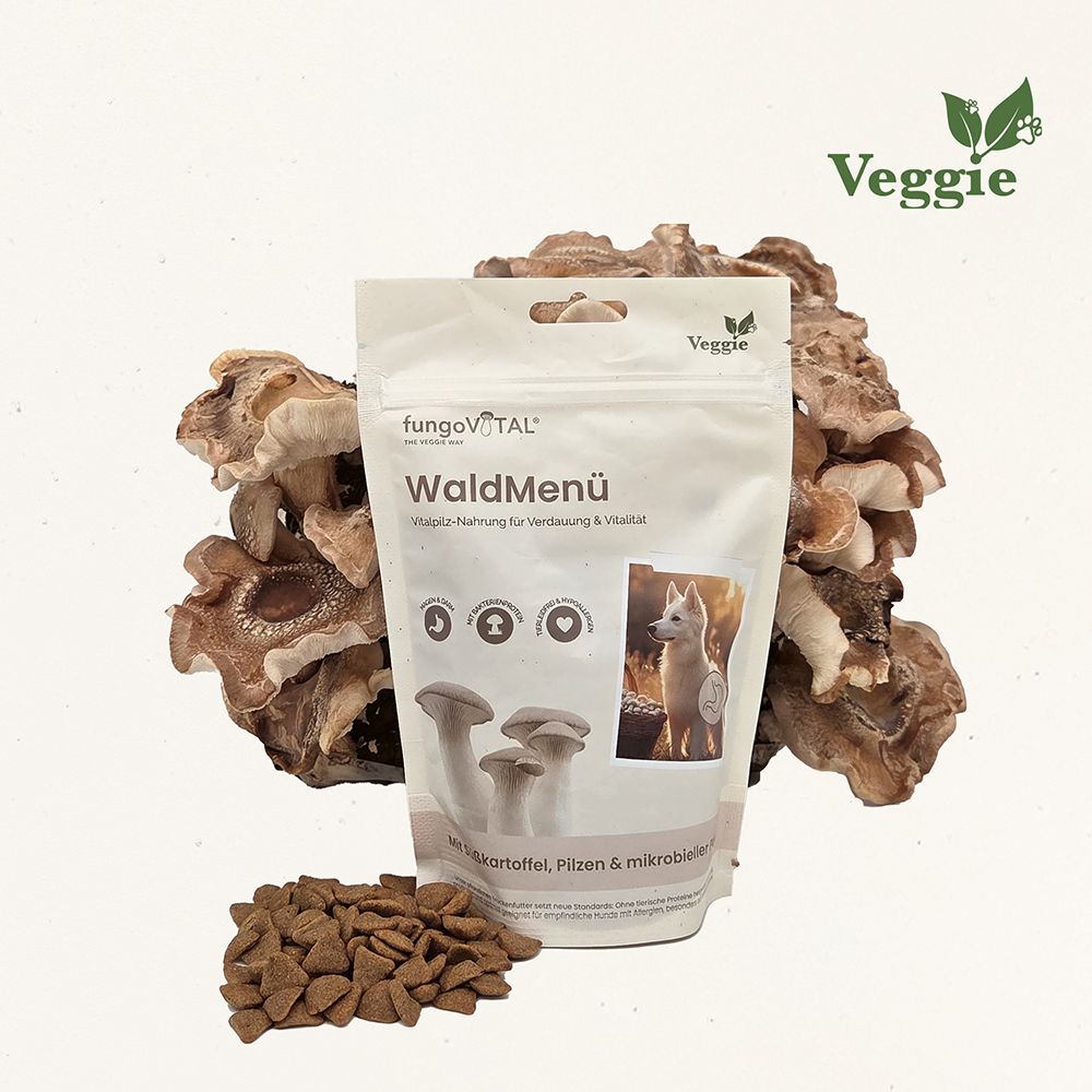 Beutel mit WaldMenü-Hundefutter, Pilze im Hintergrund, Futterbrocken davor. Logo: Veggie.