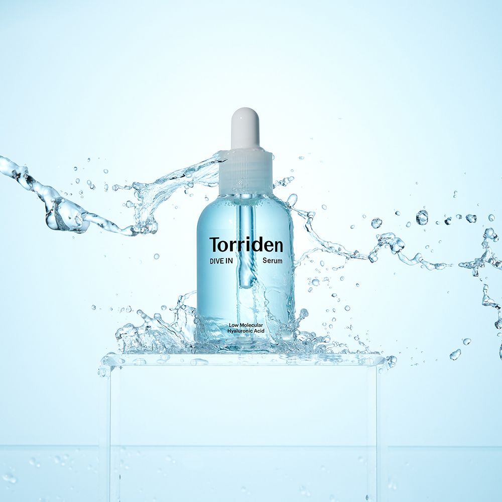Torriden DIVE IN Serum mit Hyaluronsäure spritzt aus einer Flasche mit Tropfverschluss.